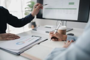 Two people looking at datasheets of marketing and sales results, analysis of business results jointl